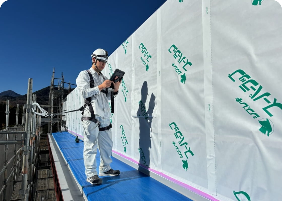 建設現場でタブレットを見ながら作業をする作業員